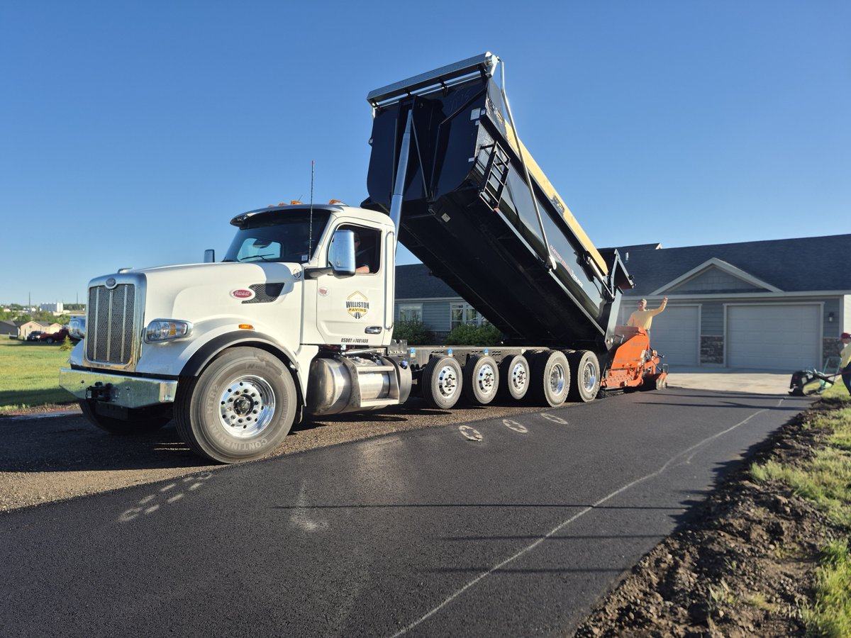 Dump truck feeding an asphalt paver on a job site