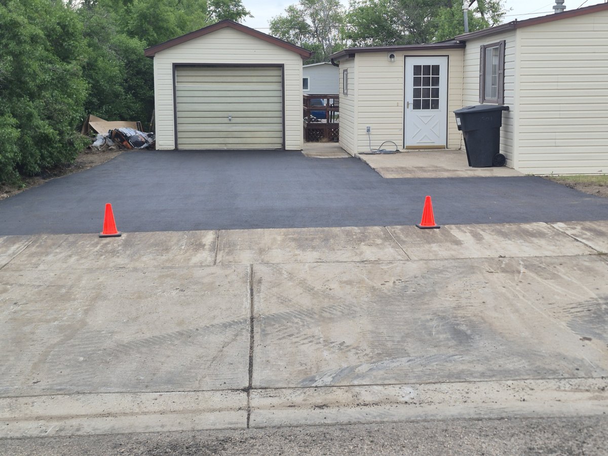 New asphalt driveway leading to an attached garage