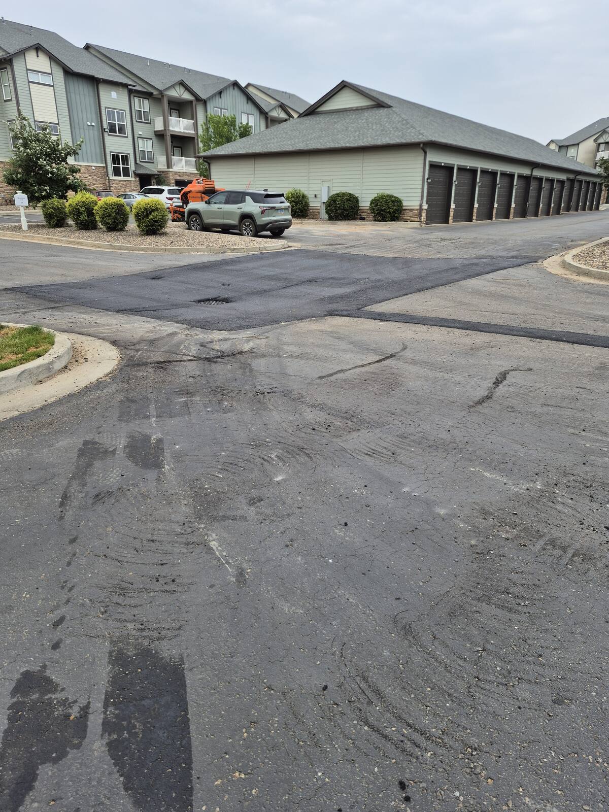 Patched intersection of two drive lanes at an apartment complex with the buildings and garages behind