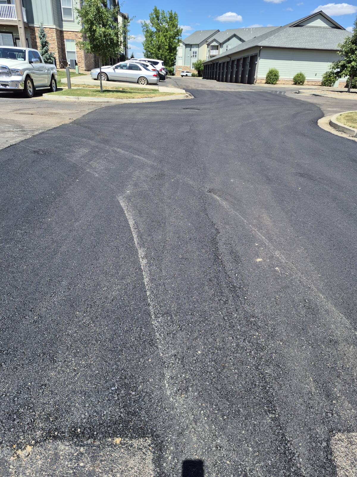 Fresh asphalt patch running through a drive lane at the complex