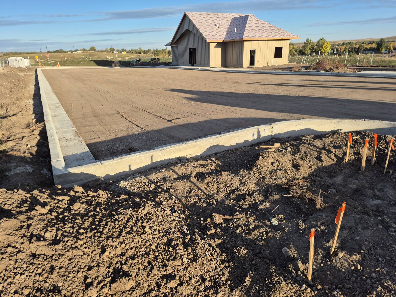 Graded gravel base inside new concrete curb at the Blacktail Dam community building before paving