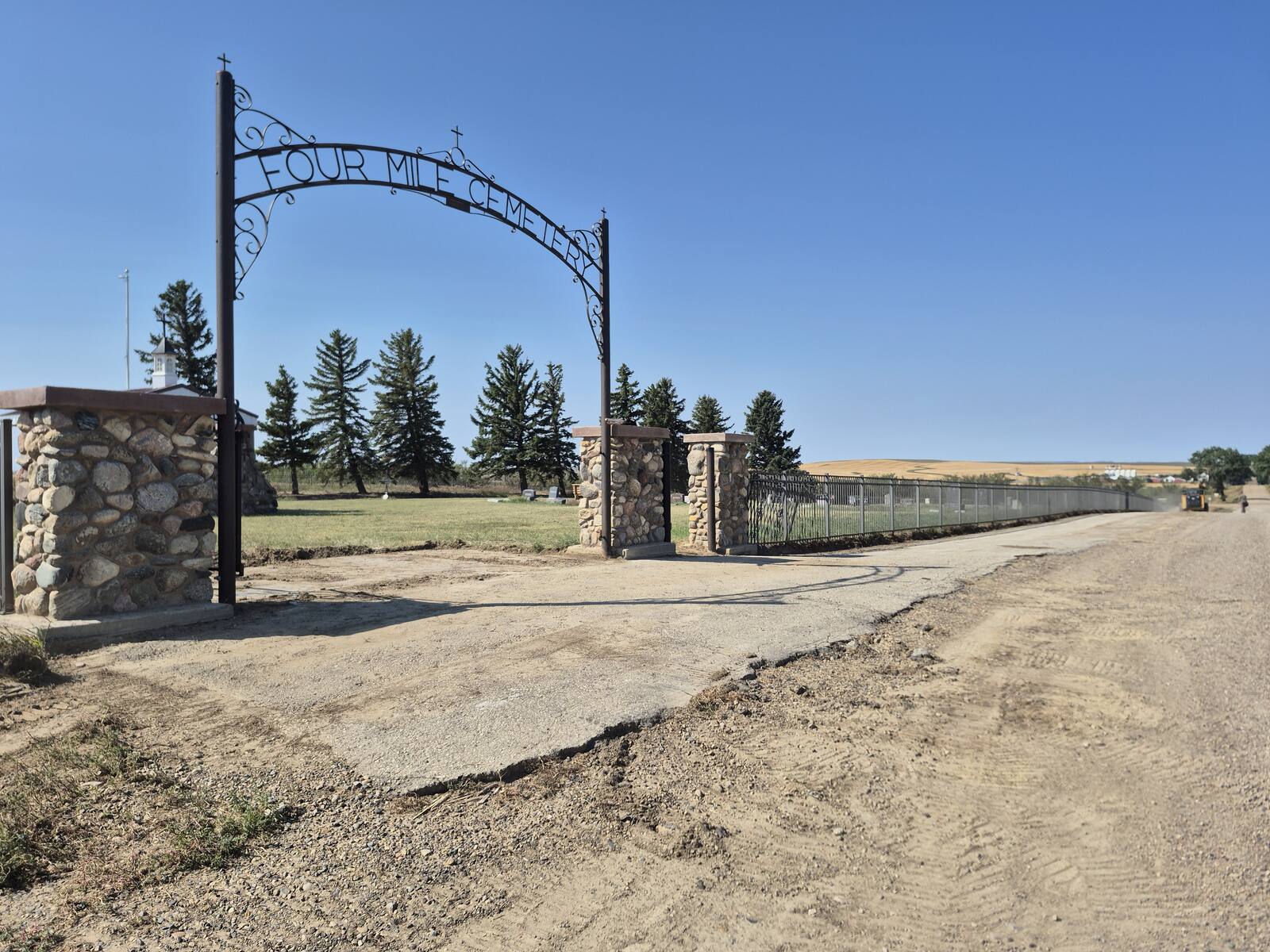 Gravel and broken pavement at the Four Mile Cemetery entrance arch before the overlay
