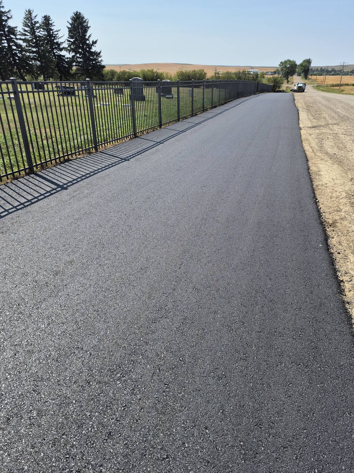 New asphalt drive running along the cemetery fence