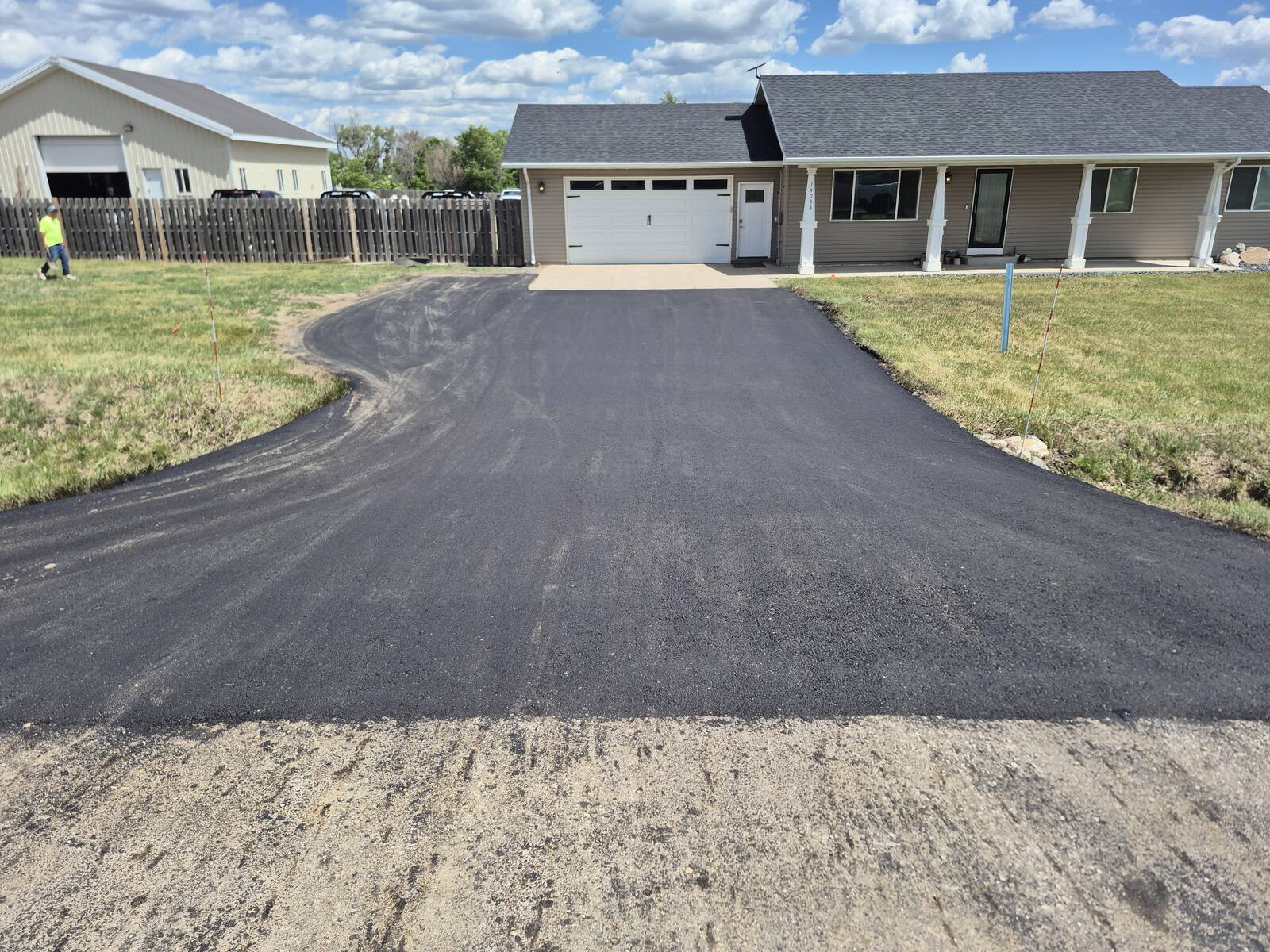 New asphalt driveway curving up to a house and detached garage