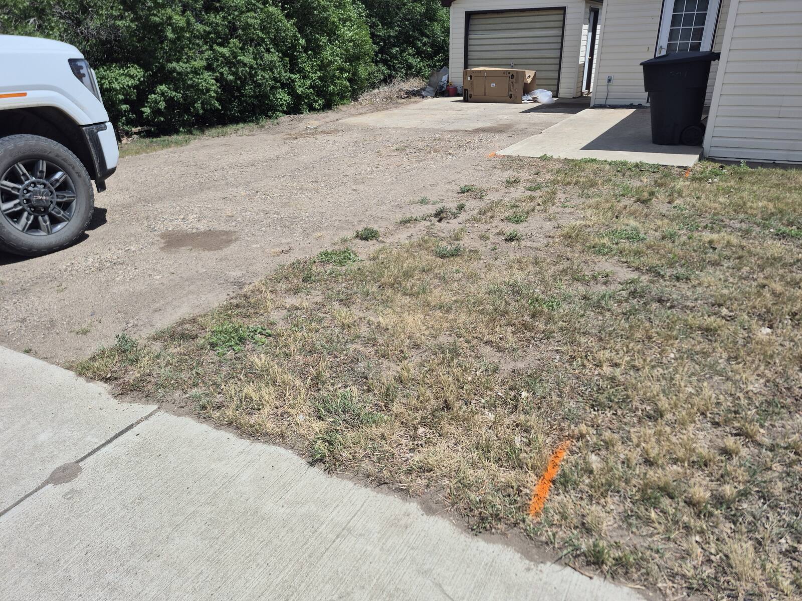 Gravel and patchy grass in front of a detached garage before the tear-out
