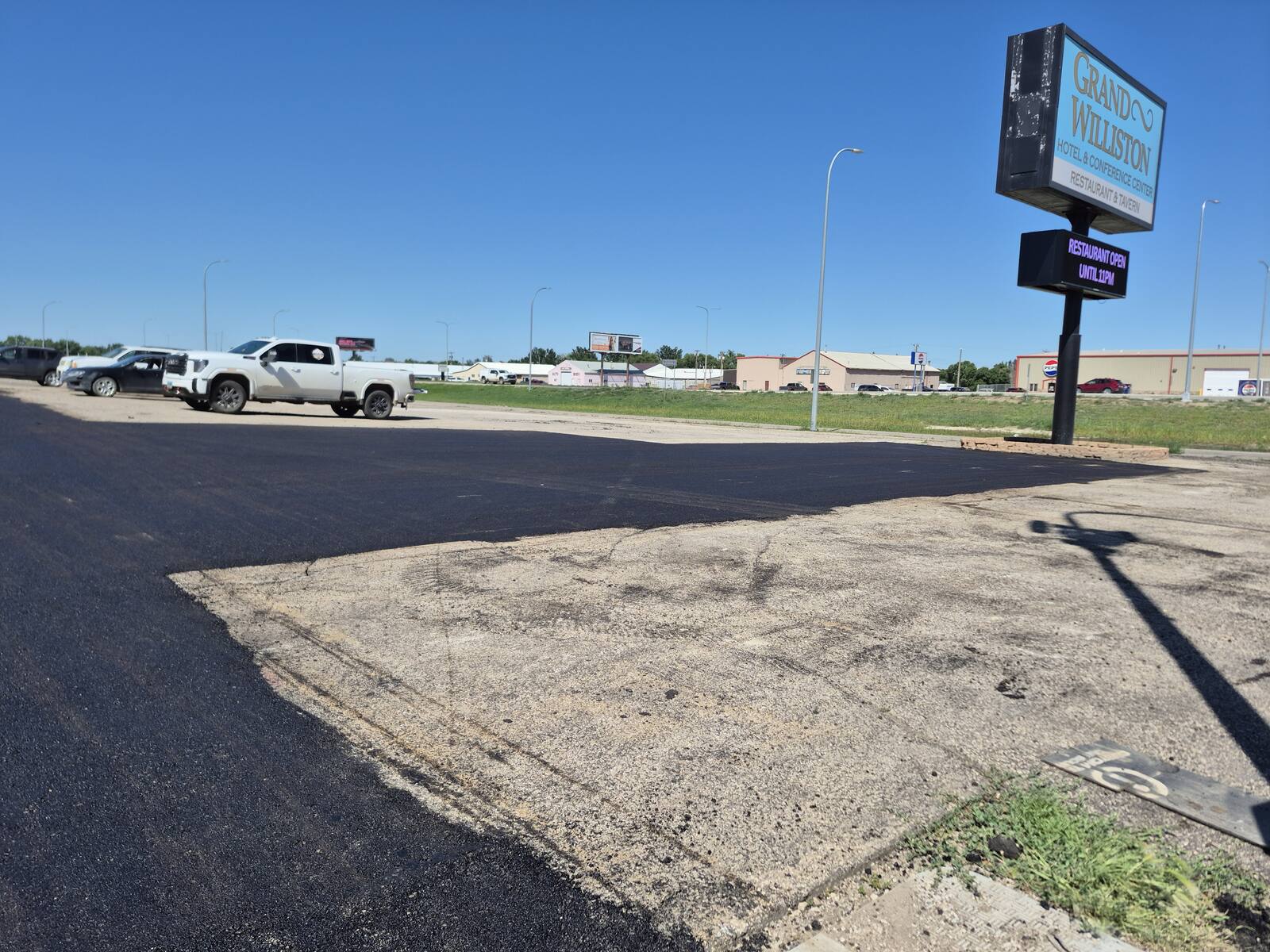 New asphalt in the Grand Williston Hotel parking lot with the hotel sign in the background