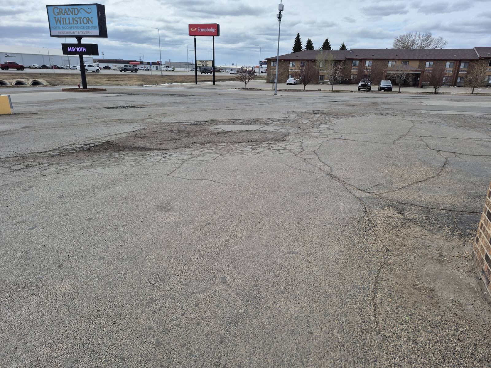 Cracked and broken asphalt in the Grand Williston Hotel parking lot before repair