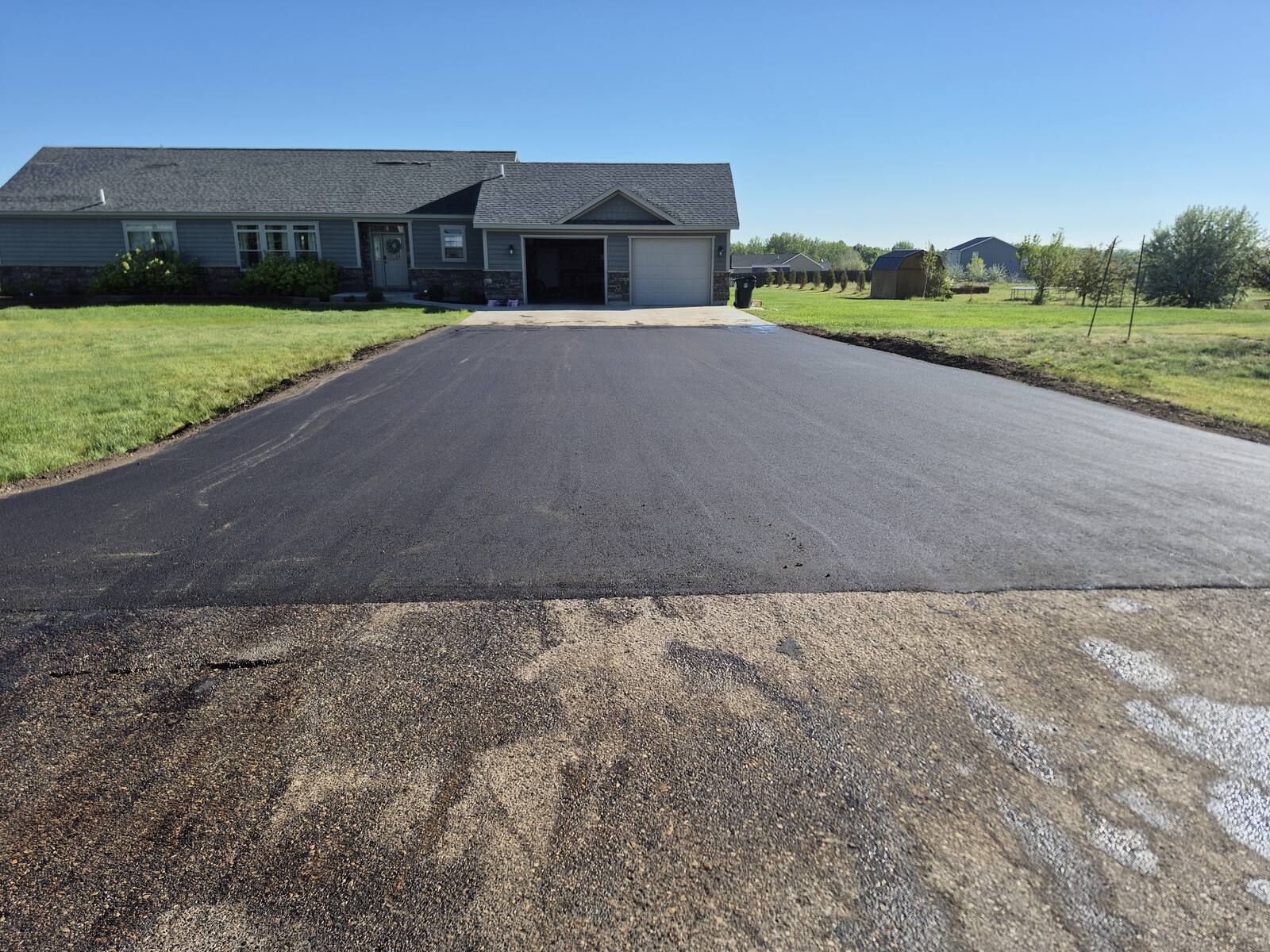 New asphalt driveway leading up to the same home