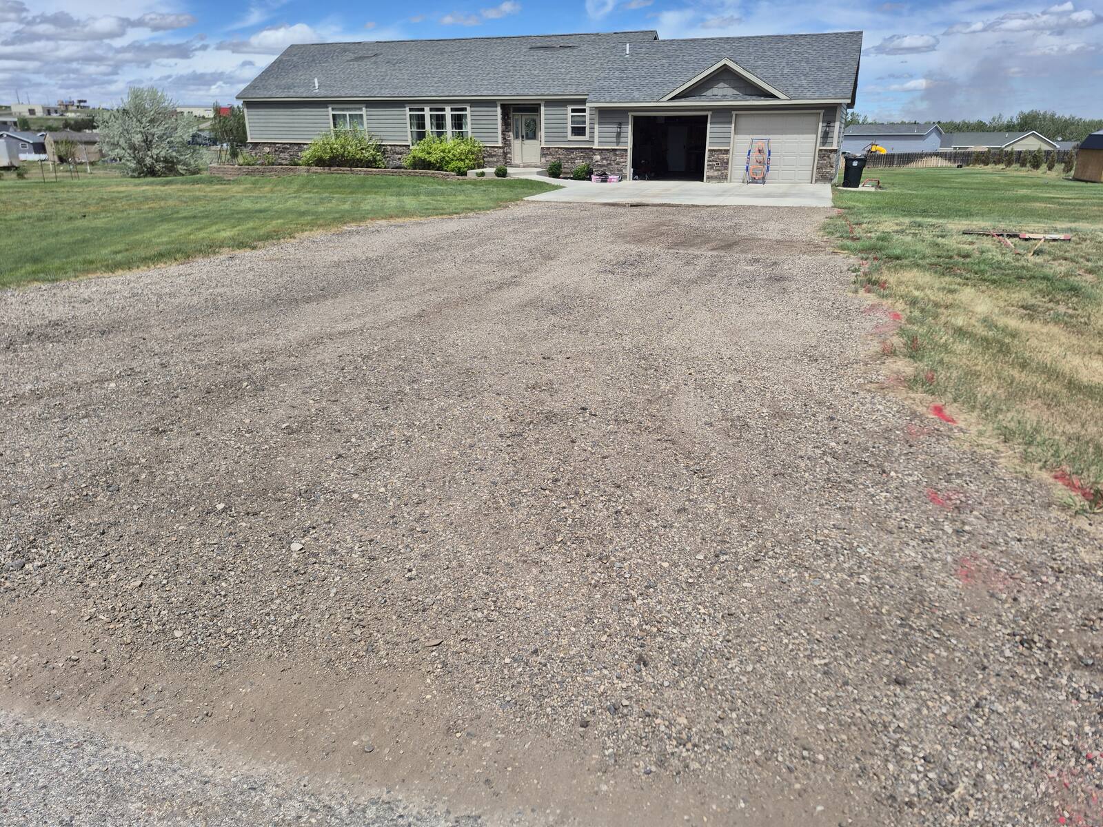 Gravel driveway leading up to a single-story home before paving