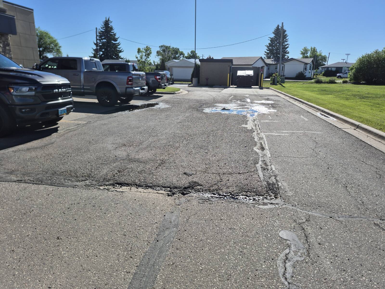 Cracked asphalt with standing water at the edge of a parking lot before milling