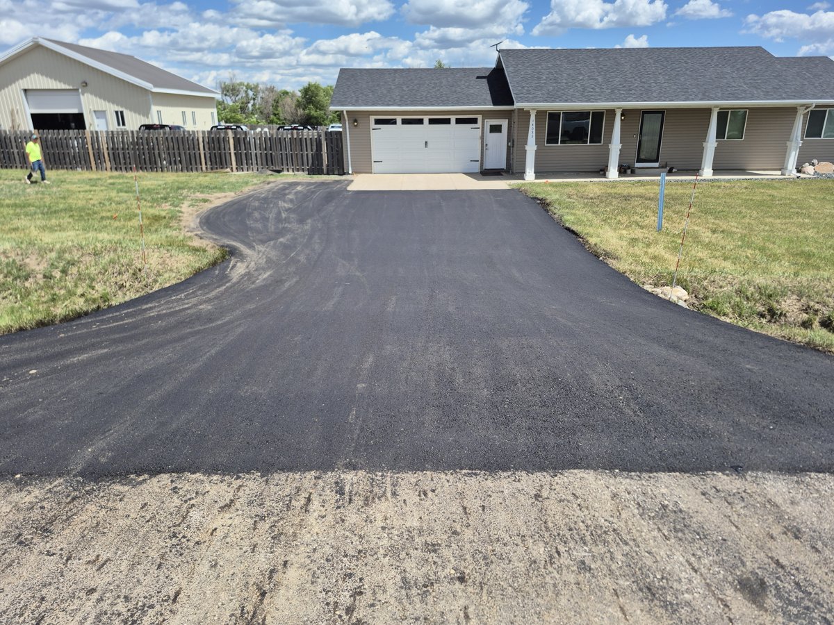 Long new asphalt driveway installation at a Williston home