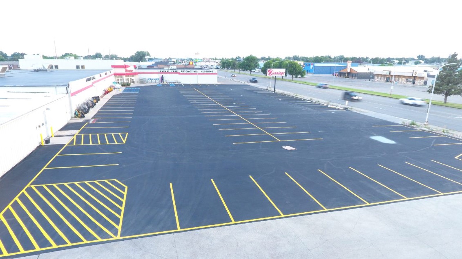 Fresh yellow striping across the sealcoated Runnings parking lot