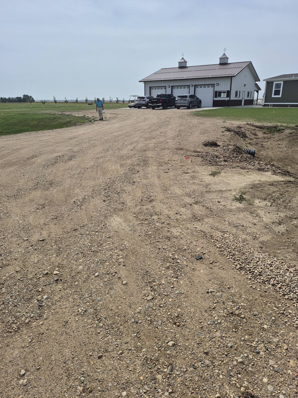 Gravel driveway leading up to a shop building before paving