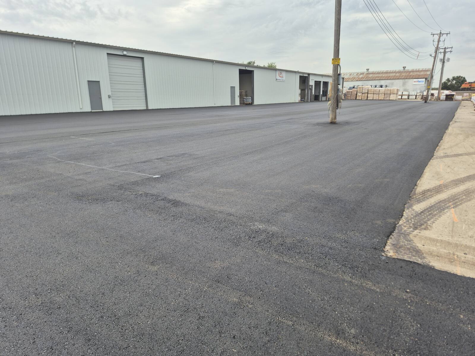 Fresh asphalt yard in front of a white metal commercial shop building